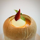 Vanilla ice cream floating in mango juice and sago served in a fresh coconut.