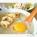 A bowl of porridge with steamed chicken plus company of a friend.