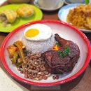 Nasi lemak is served with chicken, ikan bilis, peanuts, achar and sunshine egg.