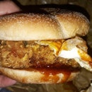 Nasi Lemak Burger with crispy fried chicken, fried egg, and cucumber slices.