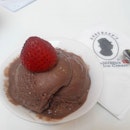 A scoop of rich creamy tasty Belgium Chocolate Ice-cream topped with strawberries.