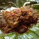 grilled fish steak wrapped in banana leaf with herbs and chili.